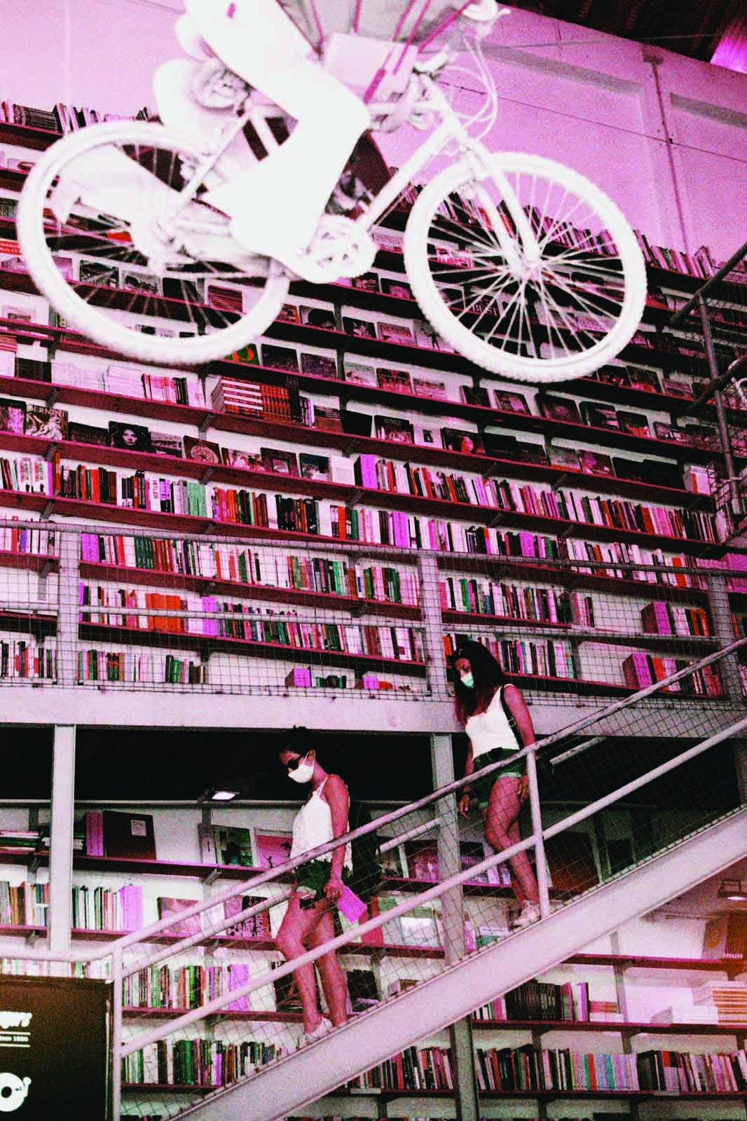 Interno della libreria Ler Devagar con scaffali pieni di libri e una bicicletta appesa al soffitto.