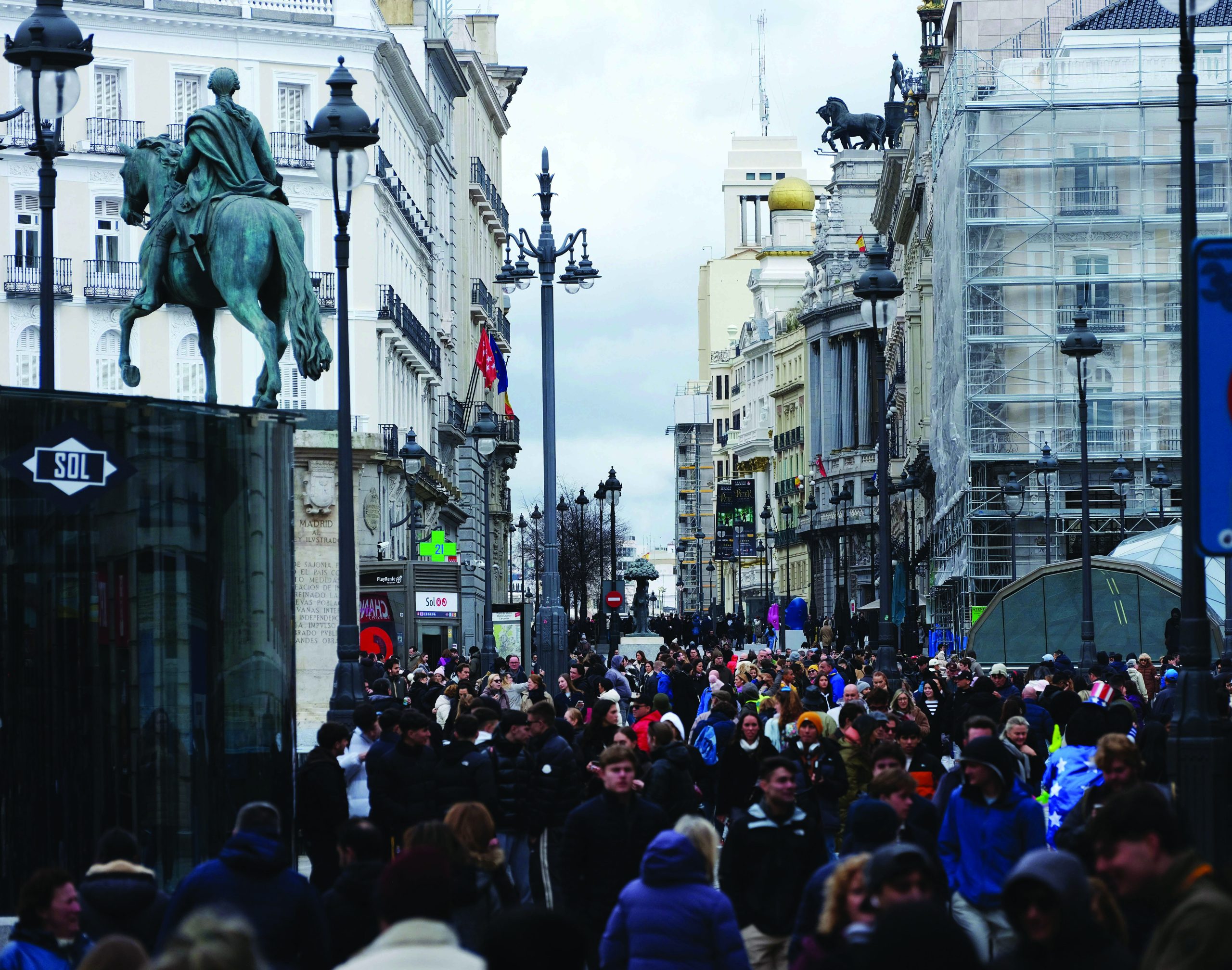 Folla di persone alla Puerta del Sol di Madrid, con edifici storici e statue in vista