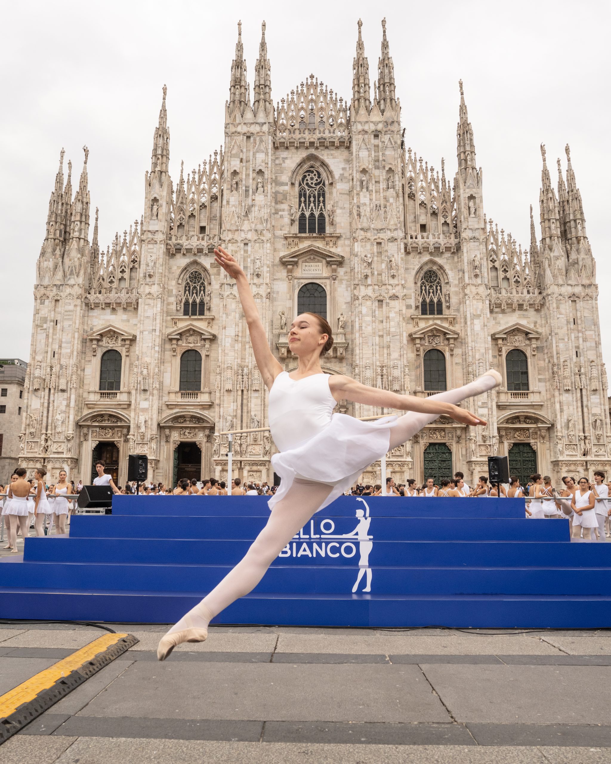 ballerina vestita di bianco salta sullo sfondo il duomo di milano