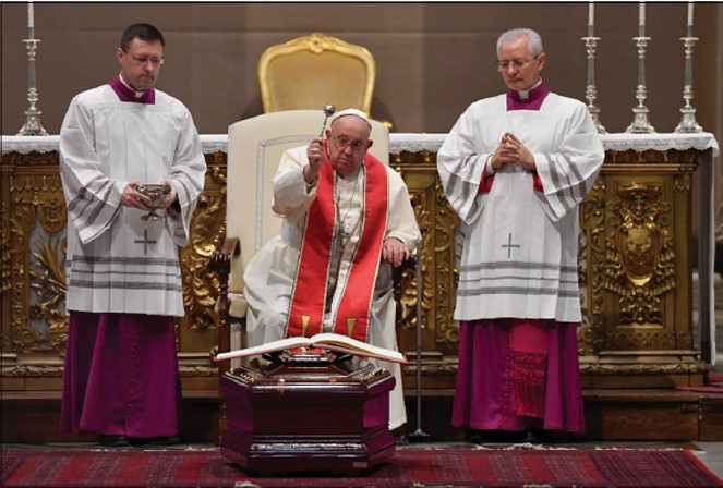 uomo vestito di bianco su sedia impartisce una benedizione.